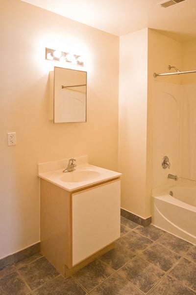 Bathroom with white and wooden cabinets & grey and beige patterned floors