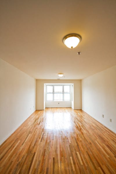 Living room with a 3 panel window, white walls and hardwood floors