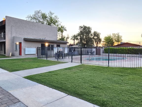 a yard with a pool and a building in the background