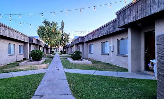 a pathway between two buildings with string lights hanging from the ceiling