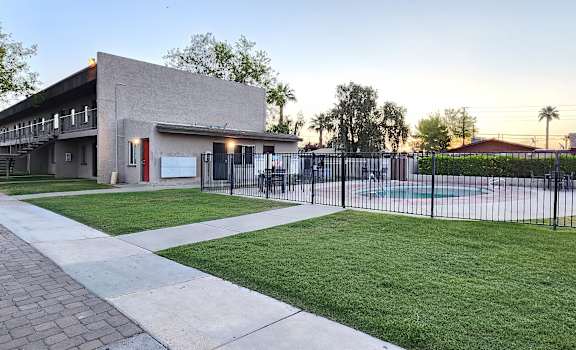 a yard with a pool and a building in the background