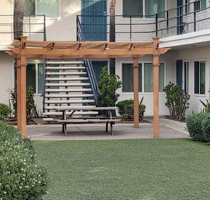 a courtyard with a picnic table and a pergola on the side of a building