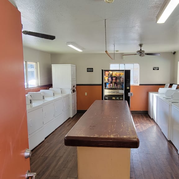 a laundry room with white washers and a long wooden table in the middle of the room