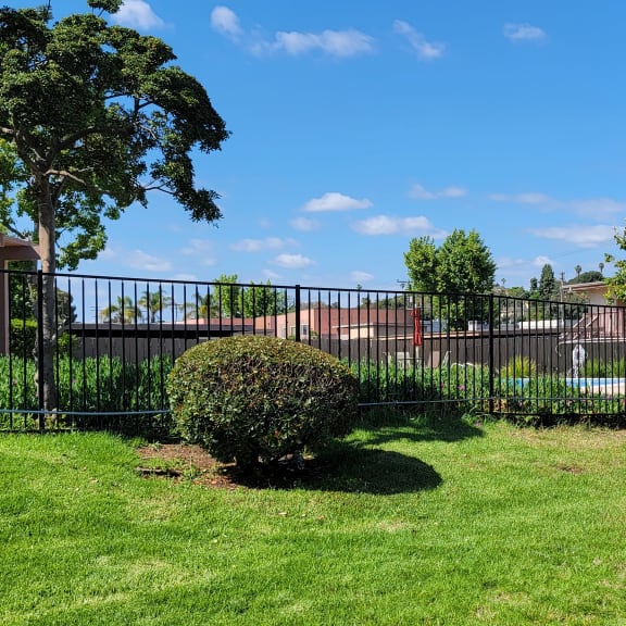 a black wrought iron fence in front of a house with a pool in the background