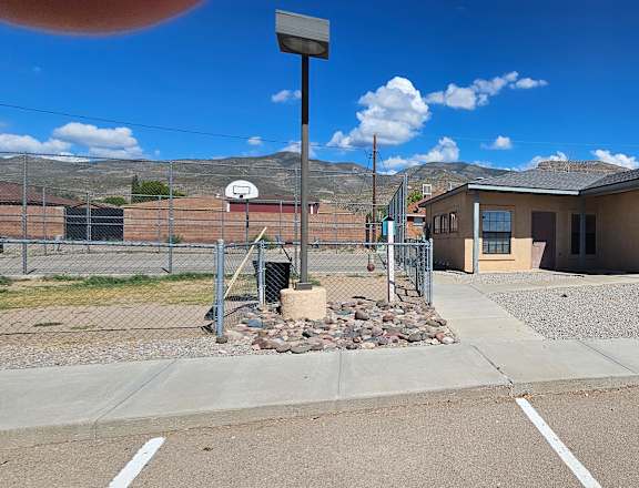 A parking lot with a building and a fence in the background.