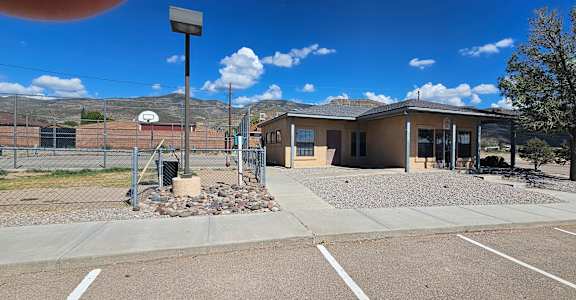 A parking lot with a building and a fence in the background.