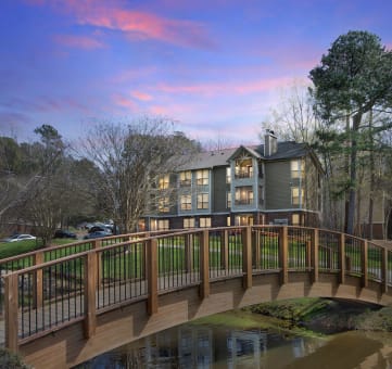 a bridge over a pond with a house in the background