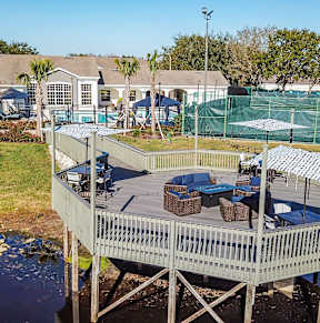 a aerial view of a pool and tennis court and a lake