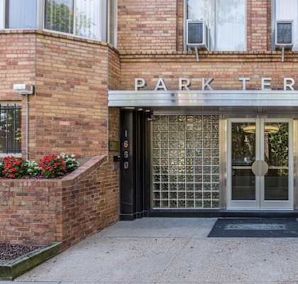 The entrance to a building named Park Terrace with a glass door and brick walls.