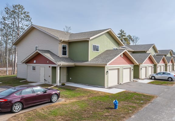 A row of houses with cars parked in front.