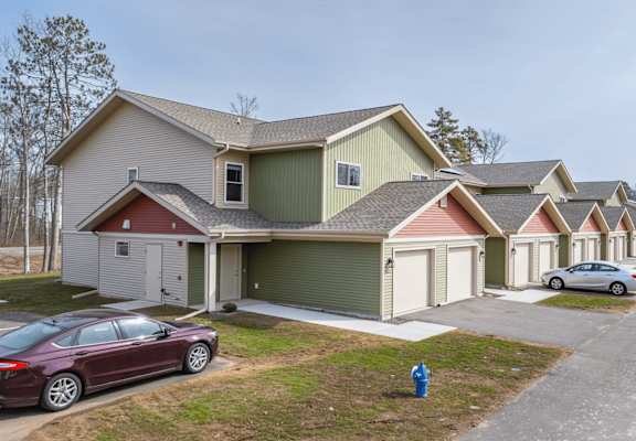 A row of houses with cars parked in front.