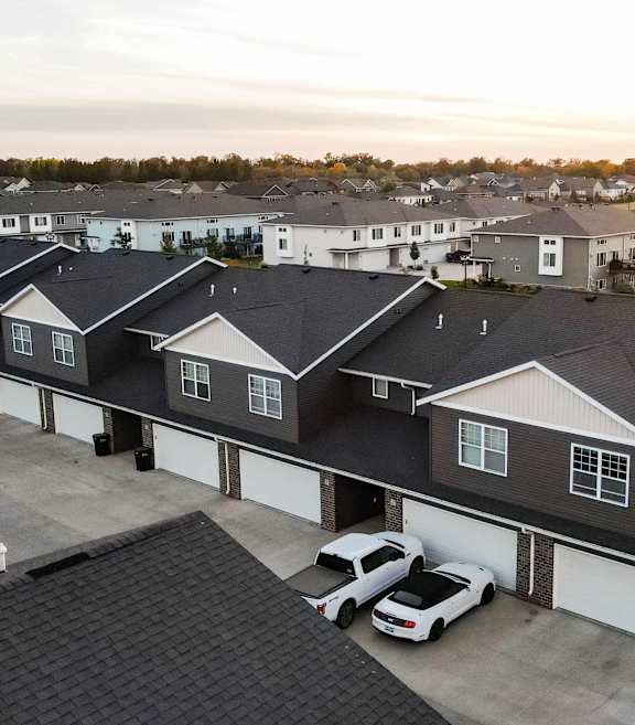 A sunset view of a residential area with houses and cars.