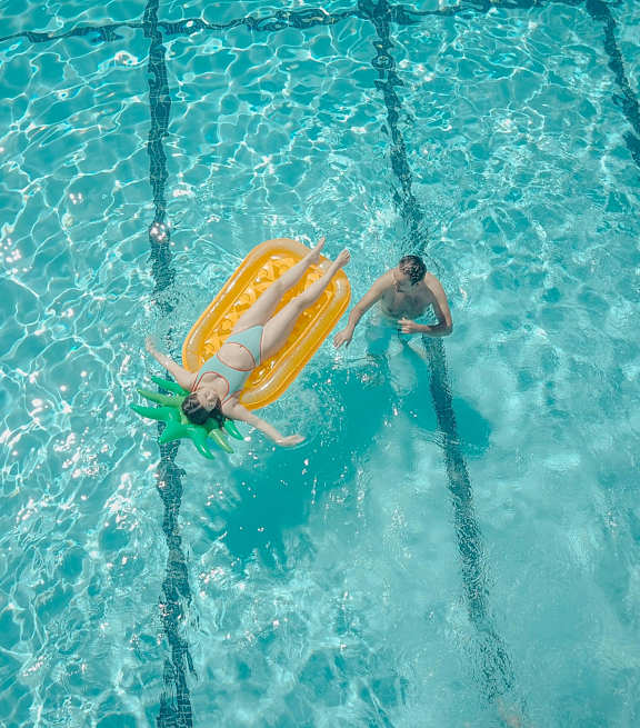 A person swimming in a pool with a yellow floatation device.