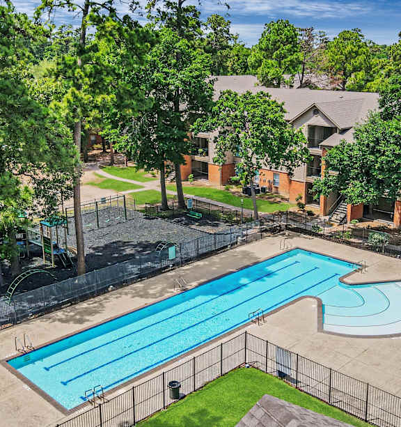 A swimming pool surrounded by a fence and trees.