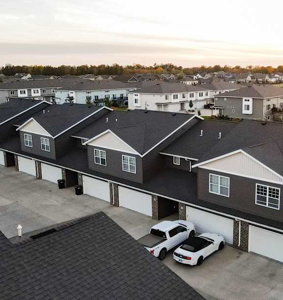 A sunset view of a residential area with houses and cars.