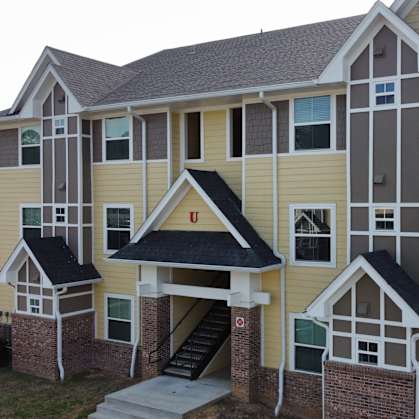 an apartment building with yellow siding and a staircase at The Fountains Apartments, Florida, 32514
