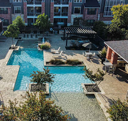 an aerial view of a swimming pool with lounge chairs and umbrellas