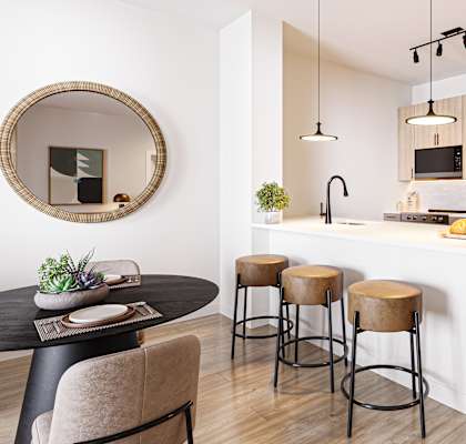 A modern kitchen with a round table and bar stools.