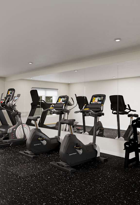 a gym with various cardio equipment in a room with a window