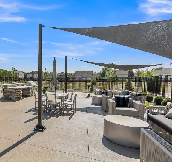 an outdoor patio with a grill and tables and chairs at Slate at Fishers District, Indiana