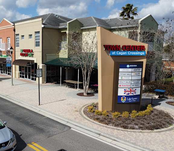 A street view of a shopping area with cars parked on the side of the road.