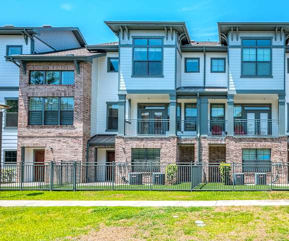 an apartment building with a sidewalk and grass in front of it