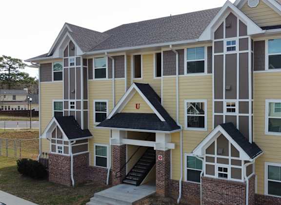 an apartment building with yellow siding and a staircase at The Fountains Apartments, Florida, 32514