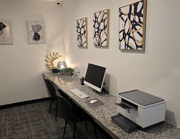 A room with a desk, chair, and artwork on the wall.