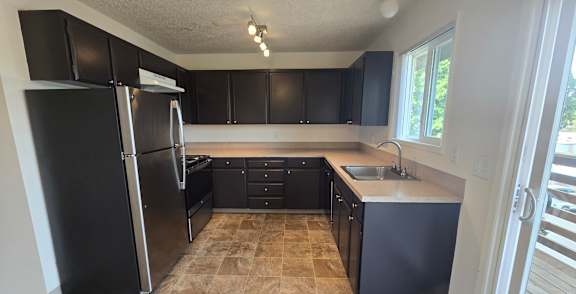 A kitchen with black cabinets and a tiled floor.