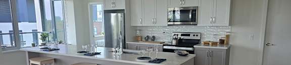 A kitchen with white cabinets and a large island with bar stools.