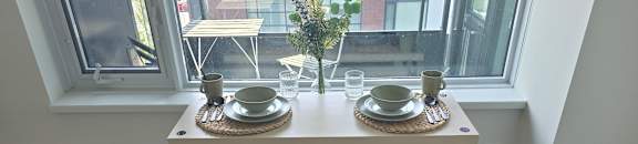 A table with a plant on it and two cups on the table.