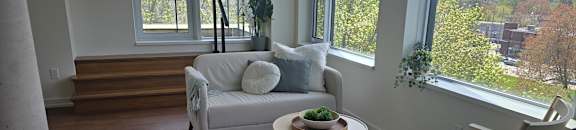 A living room with a white couch and a wooden chair.