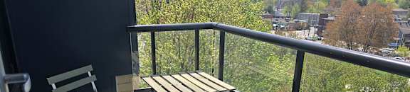 A chair and table are on a balcony overlooking a city.