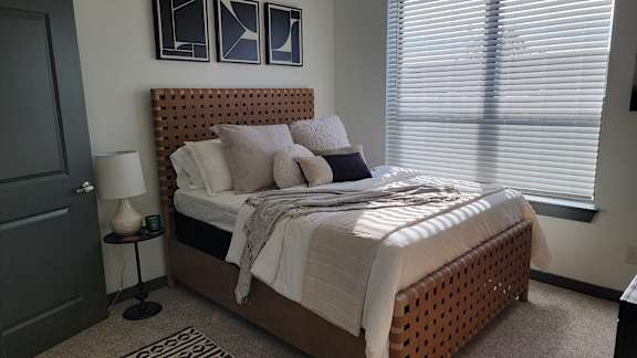 A bedroom with a bed, nightstand, and window.