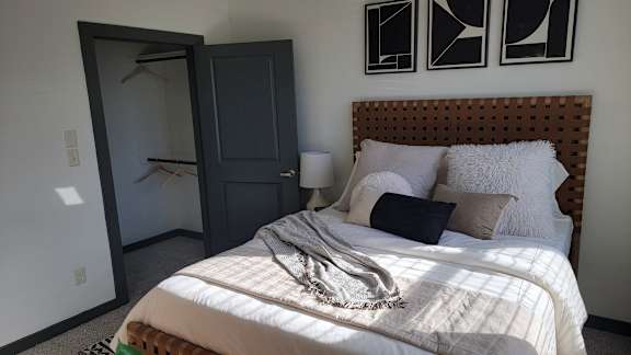 A bedroom with a bed, pillows, and a blanket.