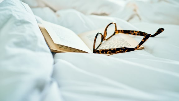Glasses and book on bed