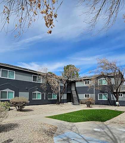 A grey building with a green lawn in front.