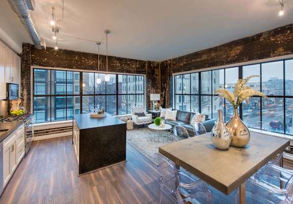 a kitchen and living room with large windows and a table