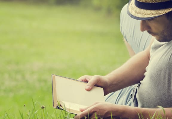 a man sitting on the grass reading a book