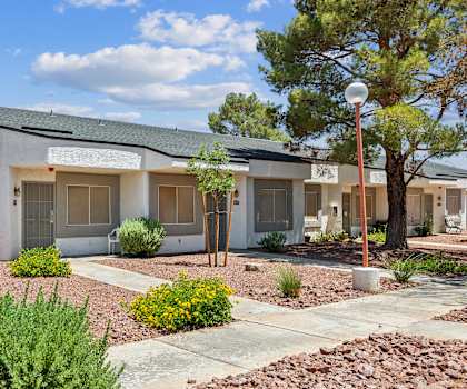 an exterior view of a white building with a sidewalk and plants