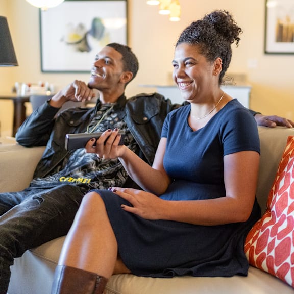 A man and a woman sitting on a couch with a tv remote at Hyde Park North.