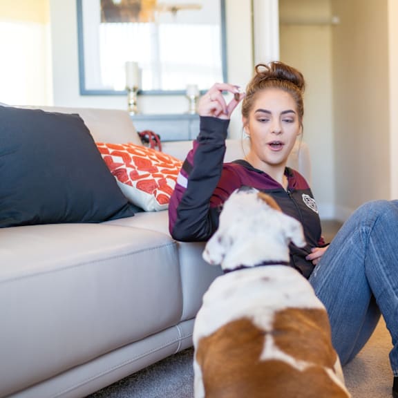 A young woman sitting on a couch with her dog at Sonora Apartment Homes. 