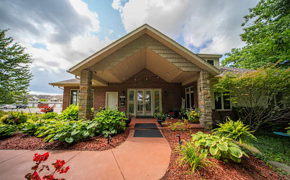 the front of a house with a walkway and plants