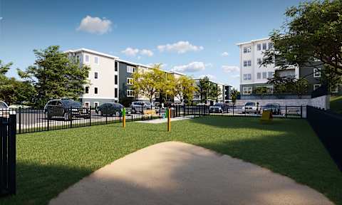 A park with a concrete walkway leading to a grassy area with trees and apartment buildings in the background.