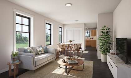 A living room with a grey couch, a coffee table, and a large window.