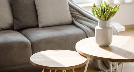 A grey couch with a white vase on a wooden table.