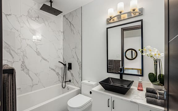 a bathroom with white marble walls and a black sink