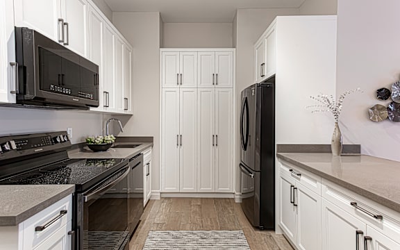 a kitchen with white cabinets and black appliances
