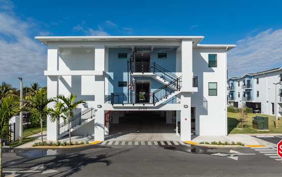 A white two-story building with a black railing on the balcony.
