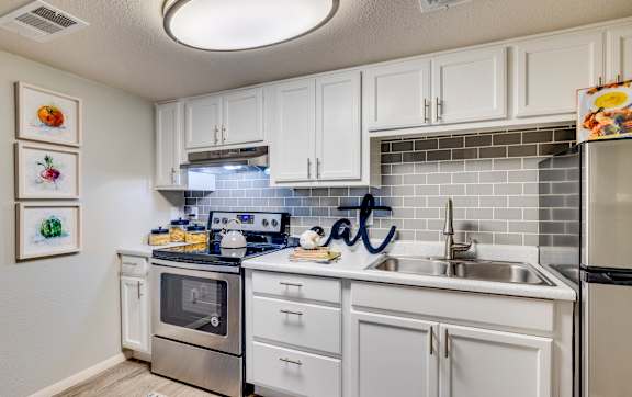 a kitchen with white cabinets and stainless steel appliances and a sink at Summers Point Apartments, Glendale, 85301